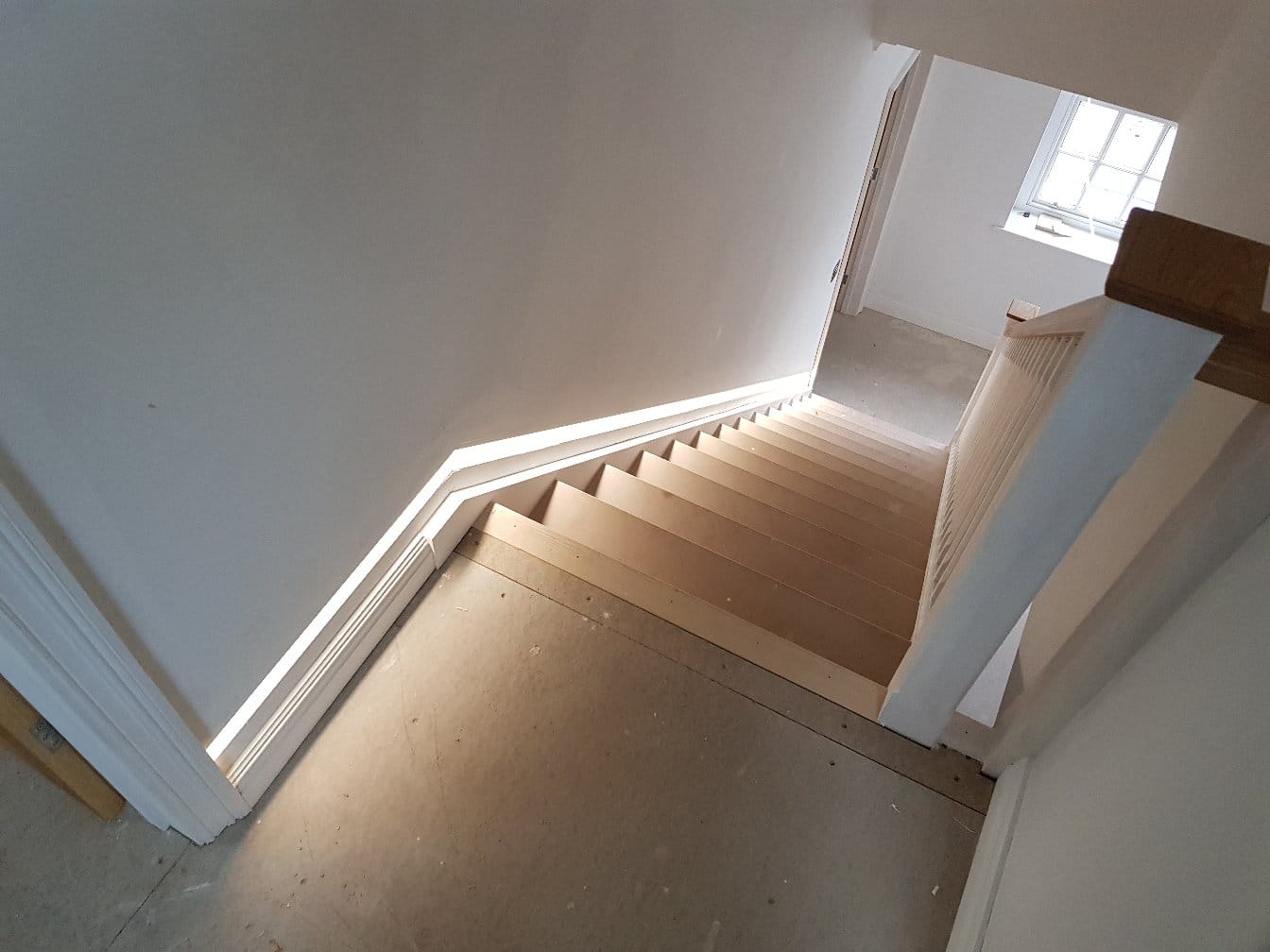Staircase lit by an LED strip along the skirting
